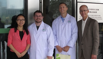 Image with caption: From left, Lingli Zhang, M.D., chief pharmacist and director of pharmacy at West China Second University Hospital and adjunct professor of pharmacy practice at UNMC, P4 students Mike Dibble and Casey Koch, and Keith Olsen, Pharm.D., chair of pharmacy practice, pose proudly with Dibble and Koch in their new white coats in Chengdu, China. Dibble and Koch are the first UNMC students to have completed pharmacy rotations in China.