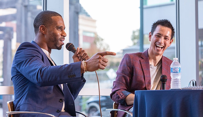 Image with caption: Former NFL wide receiver Victor Cruz, left, speaks to UNMC Department of Orthopaedic Surgery alumni and guests alongside Matthew Tao, M.D., assistant professor.